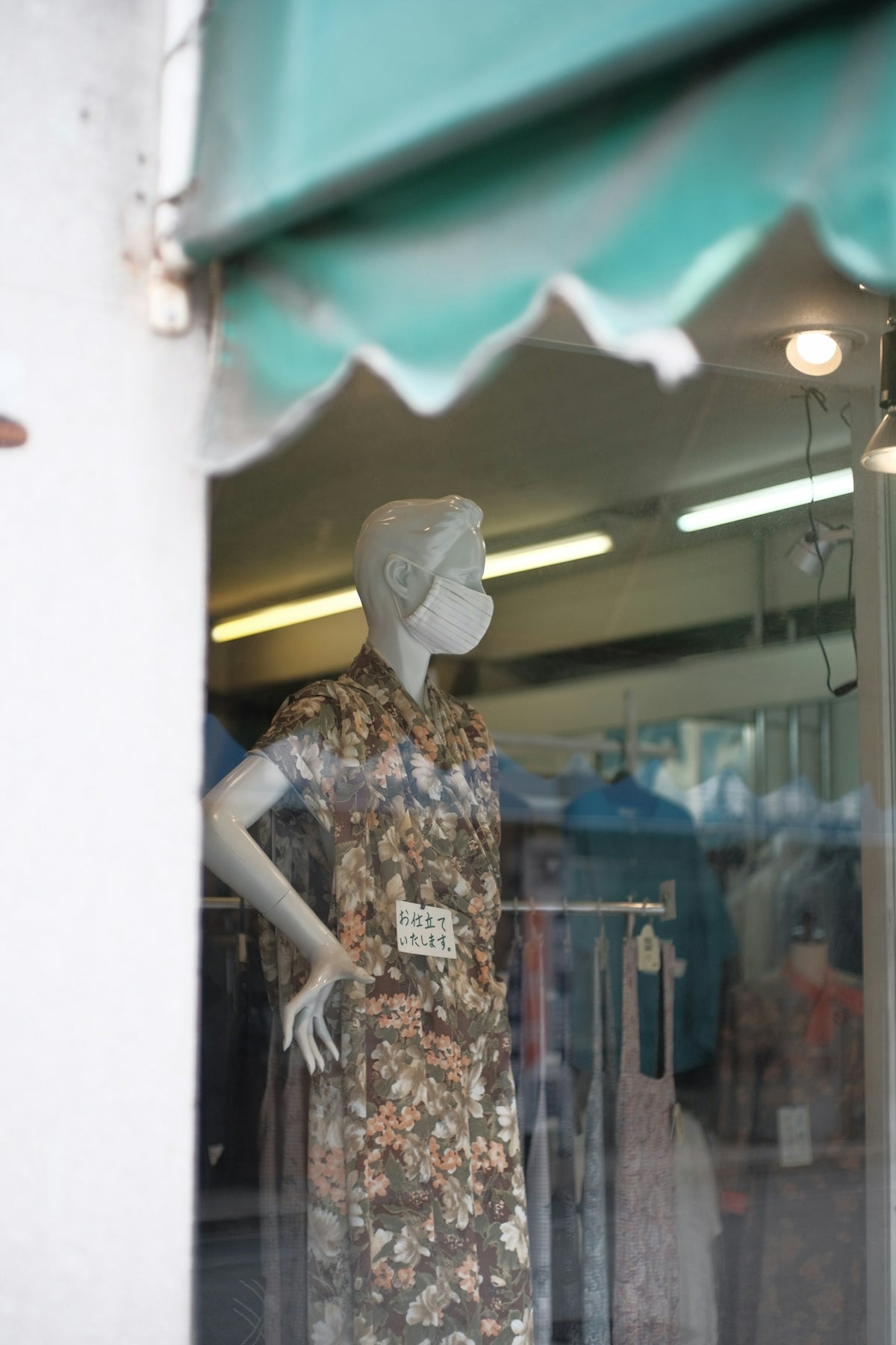 a mannequin in a shop window with a green awning