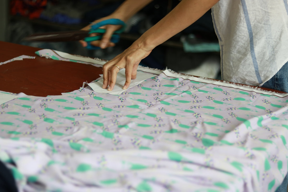 a person cutting a piece of fabric with a pair of scissors