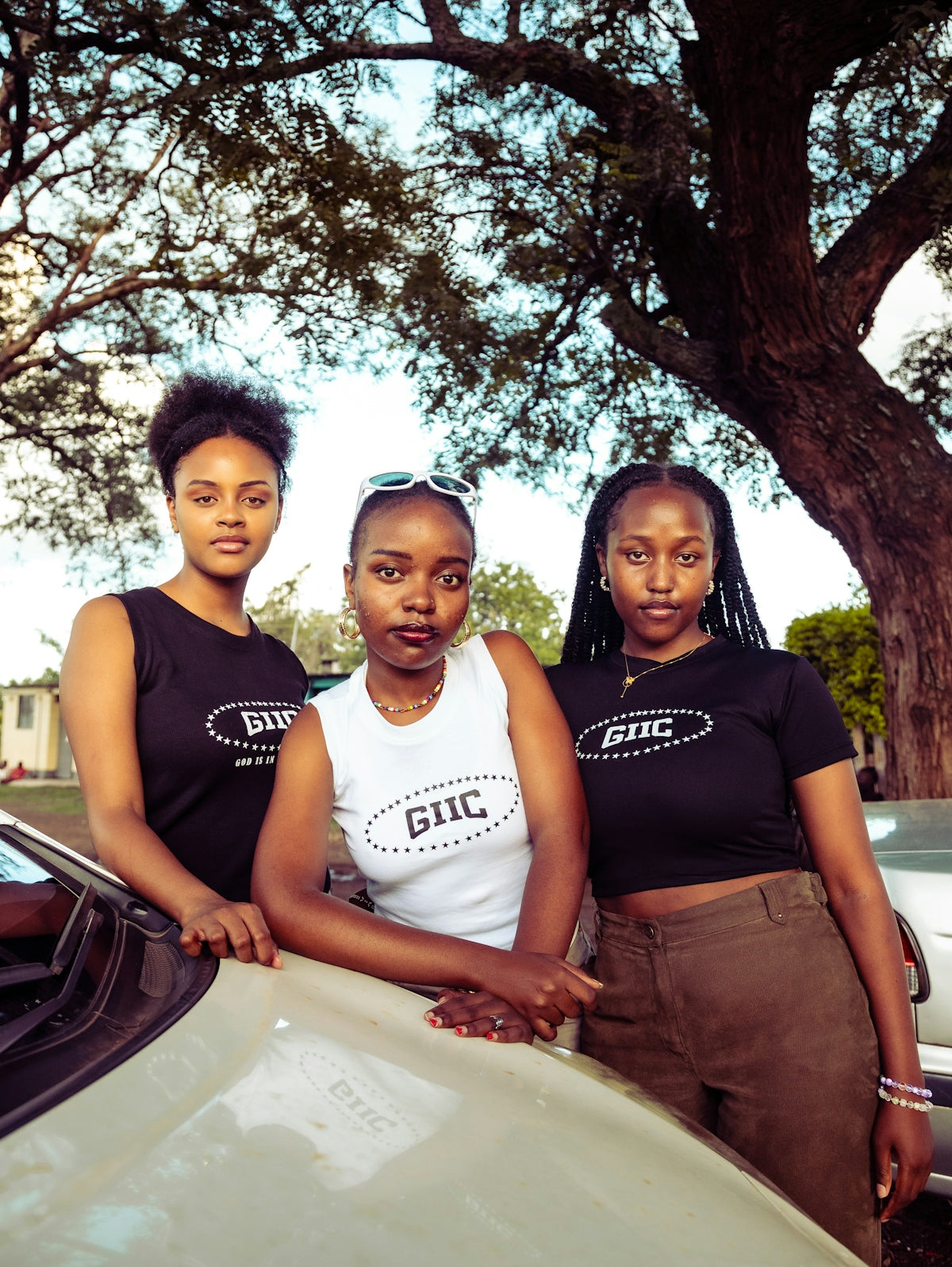 three women standing next to a white car